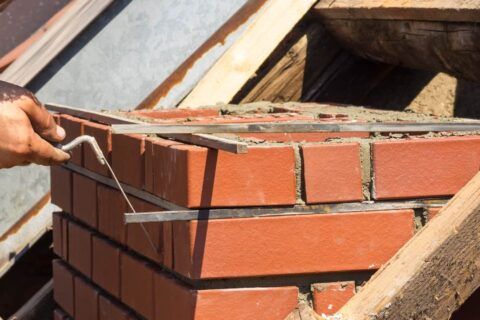 Joint rake dressing fresh mortar on red brickwork