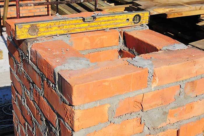 Spirit level resting on a freshly laid brick column