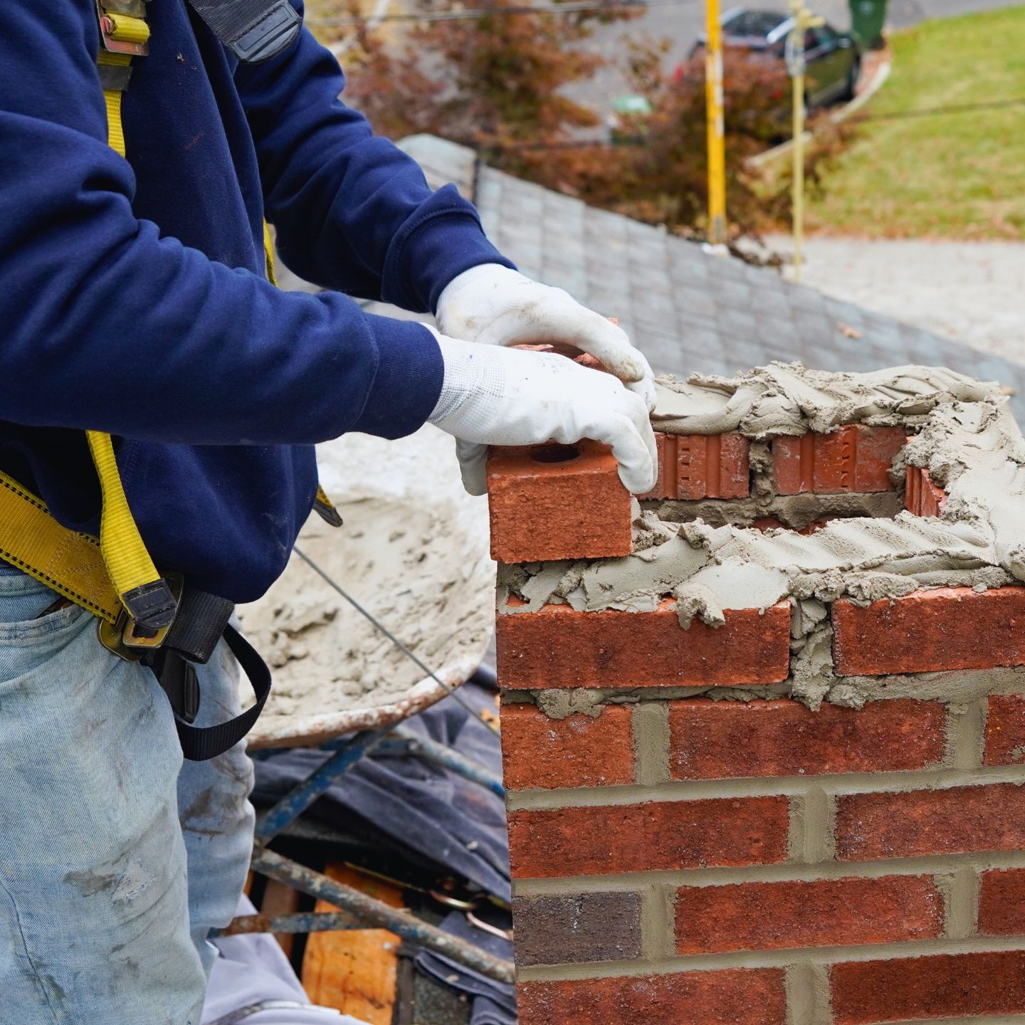 Harnessed mason laying the top courses of a chimney